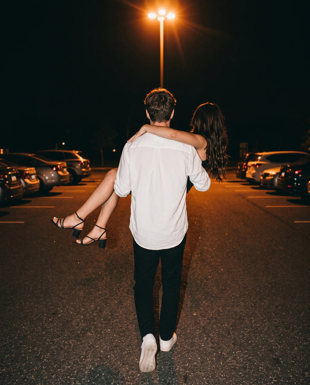 Pareja de noche en un estacionamiento, él la lleva en brazos — perfumes para hombre para una cita