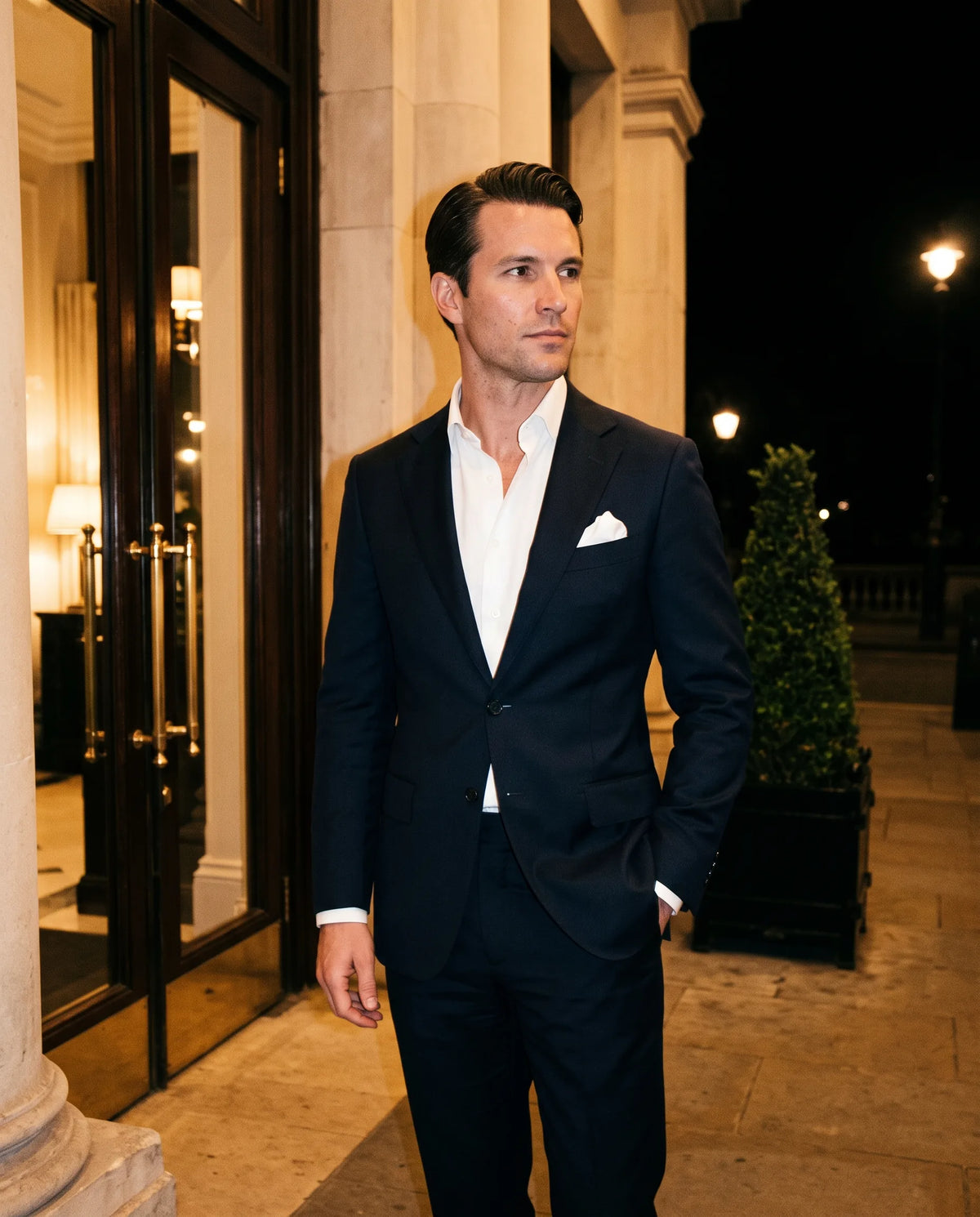 Hombre de traje azul marino en la entrada de un salón de noche — perfumes para hombre para eventos formales